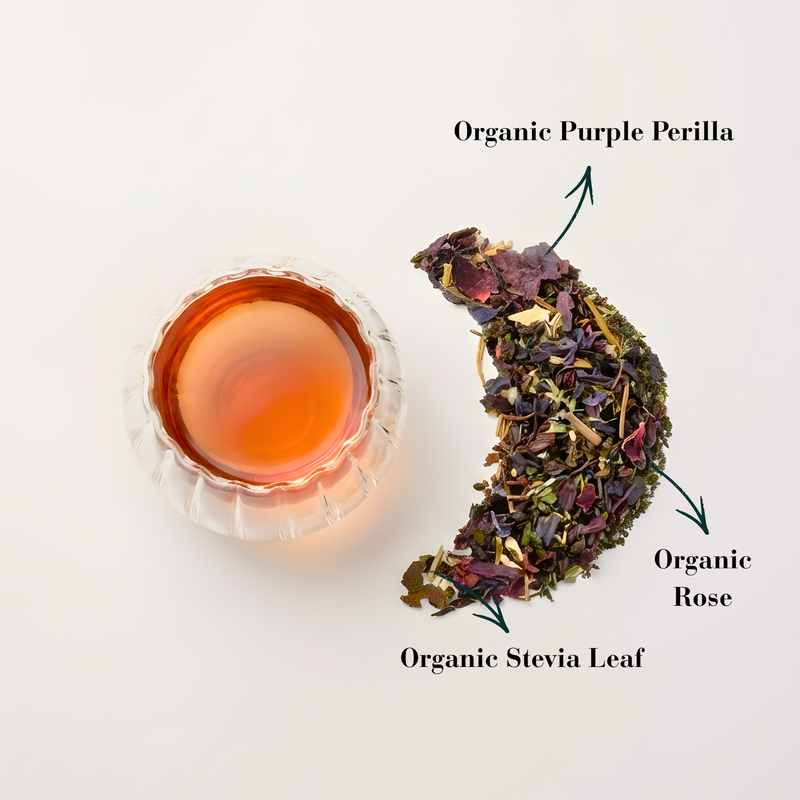 A cup of Velvet Rosilla herbal tea beside a crescent-shaped display of ingredients including organic purple perilla, organic rose, and organic stevia leaf.